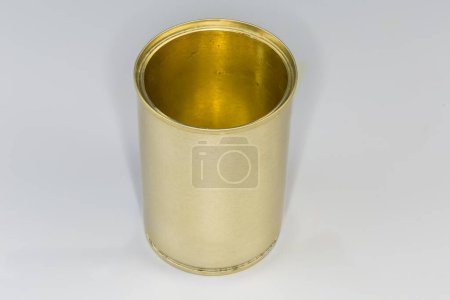 Open empty tin can from under a canned food, with yellow covering on a gray background