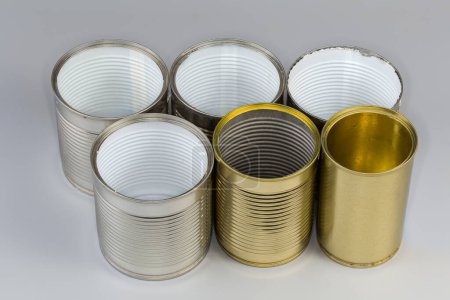 Leere Konservendosen aus Konserven öffnen, verschiedene Größen mit verschiedenen weißen und gelben Deckeln auf grauem Hintergrund