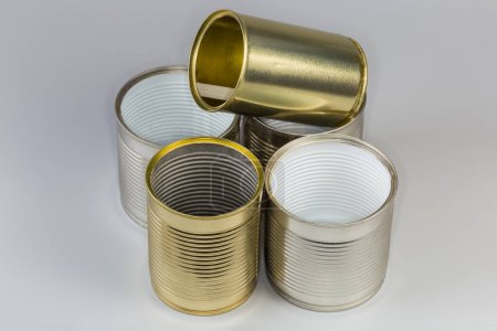 Leere Konservendosen aus Konserven öffnen, verschiedene Größen mit verschiedenen weißen und gelben Deckeln auf grauem Hintergrund