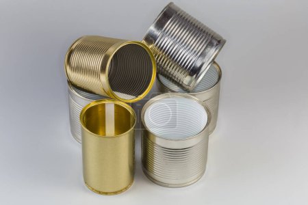 Abra latas vacías de debajo de una comida enlatada, de diferentes tamaños con varias cubiertas blancas y amarillas sobre un fondo gris