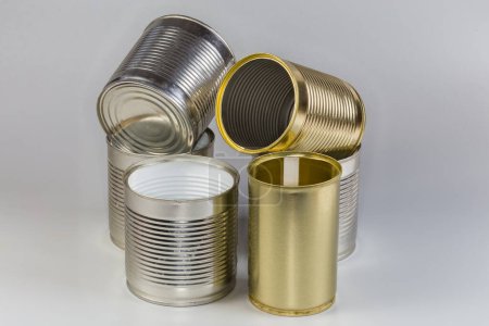 Abra latas vacías de debajo de una comida enlatada, de diferentes tamaños con varias cubiertas blancas y amarillas sobre un fondo gris