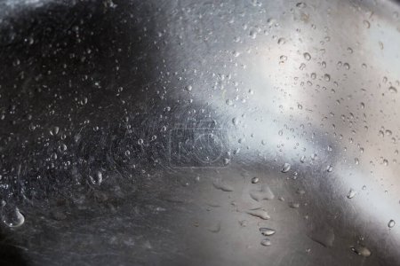 Photo for Fragment of the walls and bottom of the old stainless steel kitchen sink covered with water drops, close-up in selective focus - Royalty Free Image