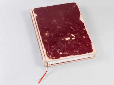 Old book with shabby red-brown hard cover and two reading ribbons on a gray background