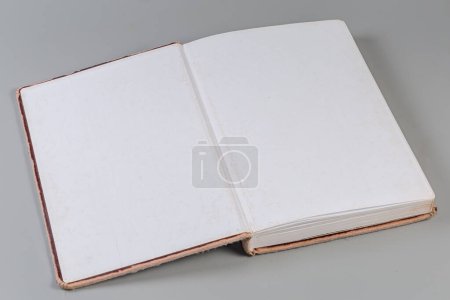 Open old book with brown shabby hard cover on a gray background