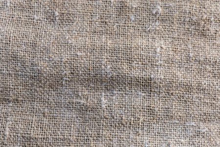 Fragment of the old coarse sackcloth woven from natural unpainted fibers with plain weave, background, texture