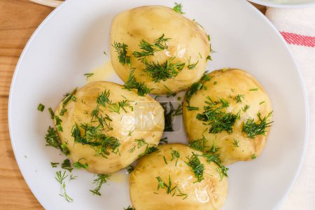 Boiled whole young potatoes with butter and sprinkled with chopped fresh dill, top view of fragment close-up
