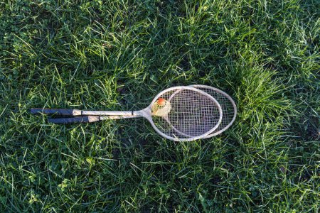 Téléchargez les photos : Une paire de raquettes de badminton avec volant blanc sur l'herbe verte aire de jeux pour enfants dans la cour en été - en image libre de droit