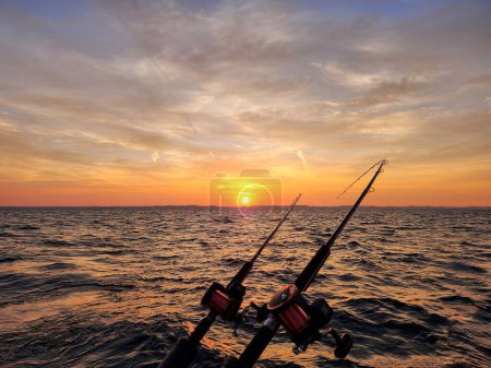 Foto de Postes de pesca con salida del sol brillando sobre el horizonte del lago Michigan - Imagen libre de derechos