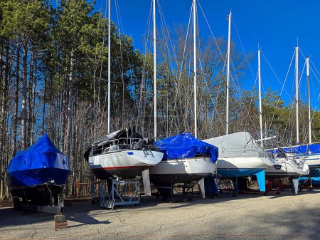 A row of boats with protective covering in an outdoor storage lot