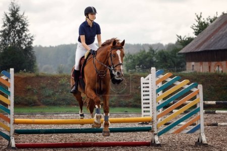 Téléchargez les photos : Jumper équestre - Jeune fille sautant avec un cheval de cerise elle effectue un saut. - en image libre de droit