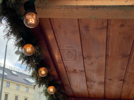Foto de Primer plano de una guirnalda de Navidad con bombillas de estilo edison vintage en un techo de madera en el mercado de Navidad en la ciudad - Imagen libre de derechos