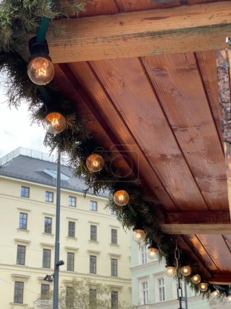 Photo for Edison style lightbulbs on christmas garland on a wooden gazebo at x-mas market in the city - Royalty Free Image