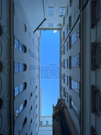 Téléchargez les photos : Vue à angle bas du ciel bleu vu dans l'écart du bâtiment résidentiel élevé. Perspective architecturale abstraite - en image libre de droit