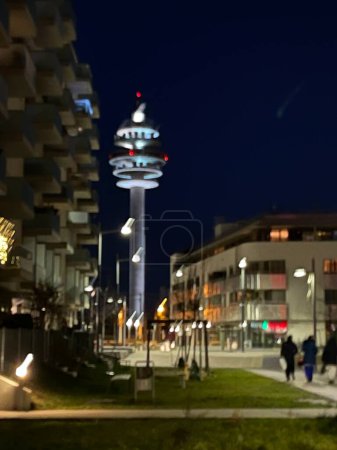Foto de Vertical blurry shot of a beautiful night city with residential buildings and communications tower glowing lights in the dark - Imagen libre de derechos