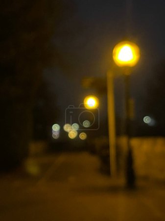 Téléchargez les photos : Blurry background shot of street lamps glowing in the dark on night city street - en image libre de droit