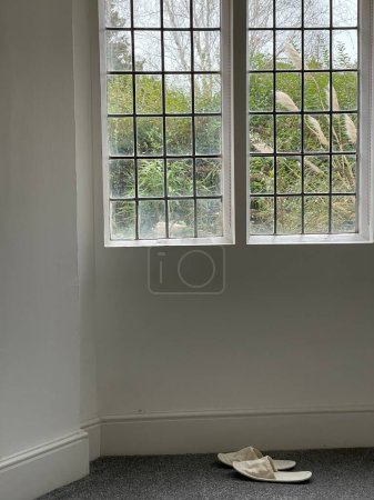 Photo for Still shot of white slippers near old fashioned window inside a house - Royalty Free Image