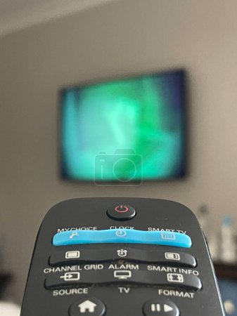 Foto de Primer plano simétrico de un control remoto de televisión, televisión en segundo plano - Imagen libre de derechos