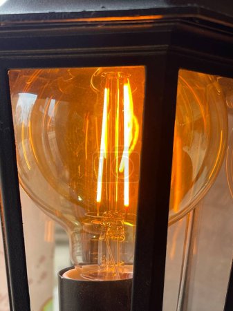 Téléchargez les photos : Recadrée de près d'une ampoule vintage de style Edison qui brille dans un lampadaire - en image libre de droit