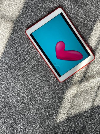 Téléchargez les photos : Coeur rose sur fond bleu illustration à l'écran de tablette numérique - en image libre de droit