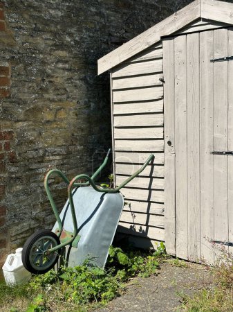Wheelbarrow near wooden backyard tool shed