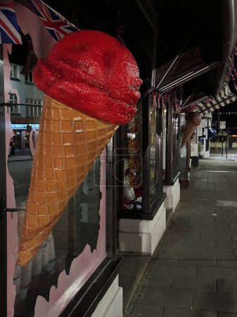 Photo for Large plastic Ice cream cone advertising ice cream shop on the town at night - Royalty Free Image