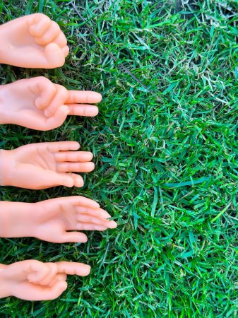 Téléchargez les photos : Gros plan de petites mains marionnettes à doigts montrant des gestes sur l'herbe - en image libre de droit