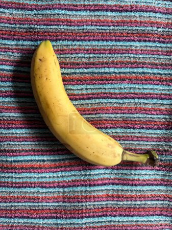 Foto de Vista superior de cerca de plátano amarillo maduro en toalla rayada - Imagen libre de derechos