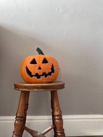 Foto de Tiro vertical de una calabaza de halloween jack-o-lantern en un taburete de madera en la casa - Imagen libre de derechos