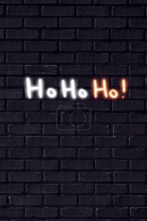 Foto de ¡Ho Ho Ho! Cartel de neón de Navidad en pared de ladrillo negro - Imagen libre de derechos