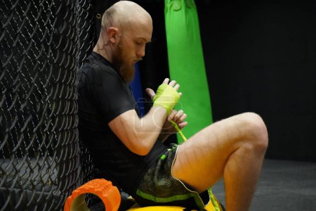 Photo for Beraded martial arts fighter wrapping his knuckles before training - Royalty Free Image