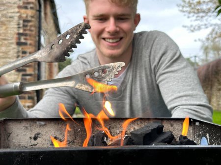 Foto de Enfoque selectivo en llamas de fuego, hombre guapo alegre sonriendo en el fondo - Imagen libre de derechos