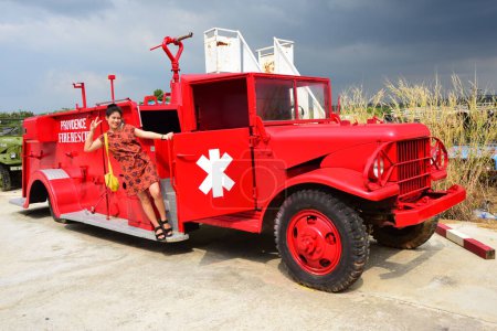 Téléchargez les photos : Femme thaïlandaise posant avec un vieux camion de pompiers rouge - en image libre de droit