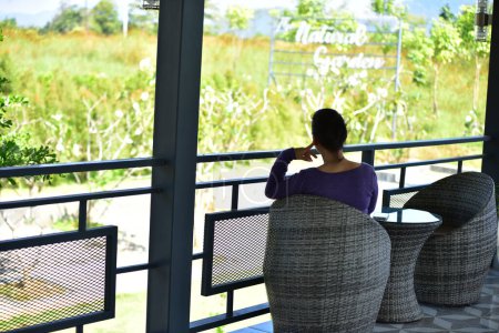 Téléchargez les photos : Vue arrière de la femme asiatique se détendre sur la terrasse de l'hôtel - en image libre de droit