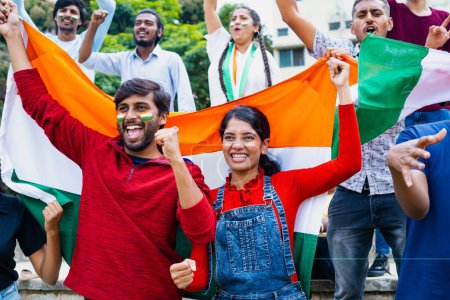 Téléchargez les photos : Jeunes couples joyeux avec drapeau indien criant ou criant pour gagner ou pour soutenir l'équipe tout en regardant match de cricket au stade concept d'excitation, championnat et match de coupe du monde - en image libre de droit