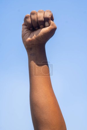 Foto de Vertical shot of Concept of black history month celebration or activist Hand rising against sky during march showing with copy space. - Imagen libre de derechos