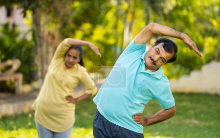 Téléchargez les photos : Couple d'aînés actifs et en bonne santé qui font du yoga ou de l'entraînement au parc - concept de conditionnement physique, de bien-être et de tranquillité. - en image libre de droit