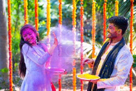 Foto de Feliz pareja india emocionada jugando holi juntos en la ceremonia del festival - concepto de diversión o diversión, unión y colorida tradición india. - Imagen libre de derechos