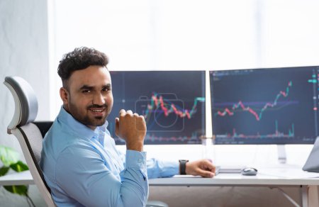 Photo for Happy smiling indian trader or stock broker by looking at camera at office - concept of successful, online trading and confident - Royalty Free Image