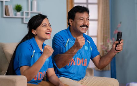 Téléchargez les photos : Focus sur le père, Père joyeux excité avec sa fille célébrant la victoire des Indes tout en regardant match de sport en direct de cricket à la télévision ou à la maison concept de moment fier, la fièvre du cricket et heureux - en image libre de droit