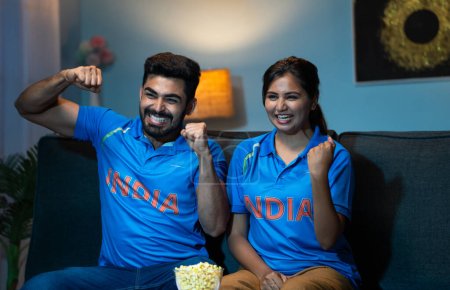 Téléchargez les photos : Couples indiens célébrant la victoire des Indes tout en regardant match de sport de cricket en direct à la télévision ou à la télévision à la maison concept de célébration de la victoire, fans excités et moment émotionnel. - en image libre de droit