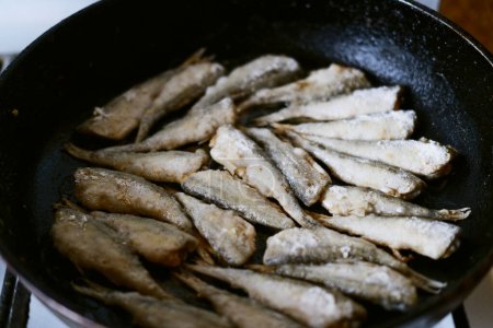 fry fish in a frying pan. small river fish in flour in a frying pan. frying pan with fried fish close-up