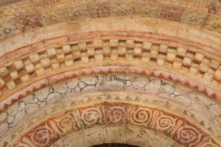 Archivo románico de una iglesia con relieve y pintado de rojo 