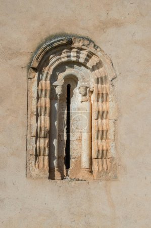 Ventana románica con columnas y arco semicircular en la pared de una iglesia