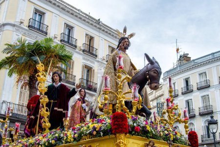 Photo for Holy week sculpture with Jesus in a donkey and other images in a procession in a  stree in Madrid. - Royalty Free Image