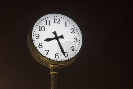 Uhr mit beleuchtetem Zifferblatt auf einer Straße in der Nacht