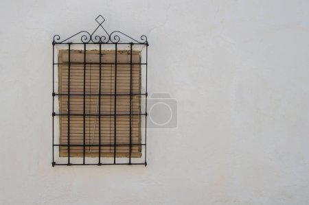 closed window with shutter and typical La Mancha grille on white wall in Spain