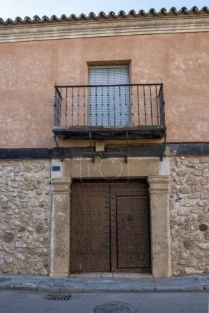 stone facade of stately house with large wooden door and balcony and iron railing