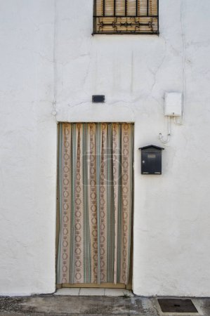 White facade of a rural house with door, curtain and mailbox in Tembleque, province of Toledo. Spain