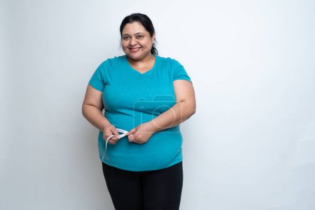 Overweight fat indian woman measuring waist with measure tape or Inch tape. isolated over white background. Plus size female. Copy Space