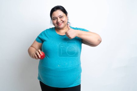 Übergewichtige Indianerin mit Apfel in der Hand und Daumen hoch. isoliert über weißem Hintergrund. Plus Size weiblich. Gesundheitsversorgungskonzept. Kopierraum
